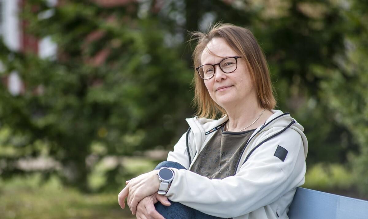 Kuvassa nainen, joka istuu ulkona penkillä.